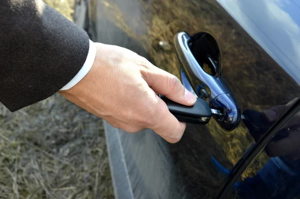 Male hand with car keys opening car door