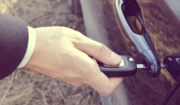 Male hand with car keys opening car door