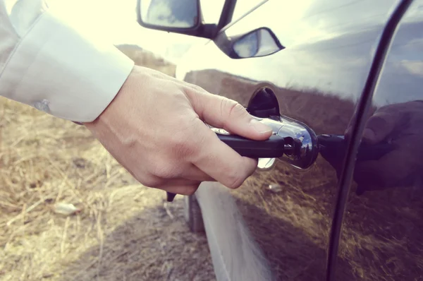 Male hand with car keys opening car door