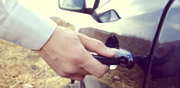 Male hand with car keys opening car door