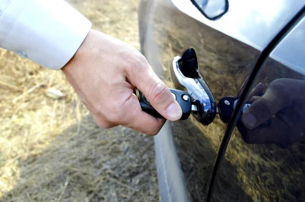 Male hand with car keys opening car door