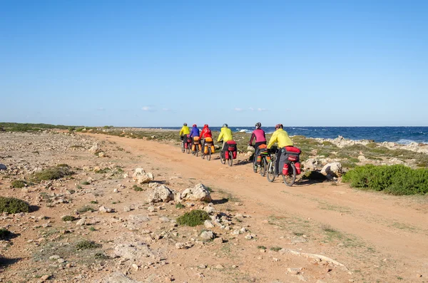 Mountain bikes rides along the winding dirt road along the sea