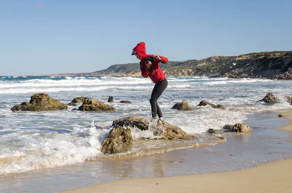 Photographer, who stands on a rock, running away from the waves. Mediterranean sea, Cyprus