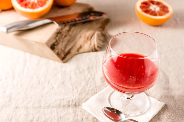 Glass of orange juice with cutting board on linen