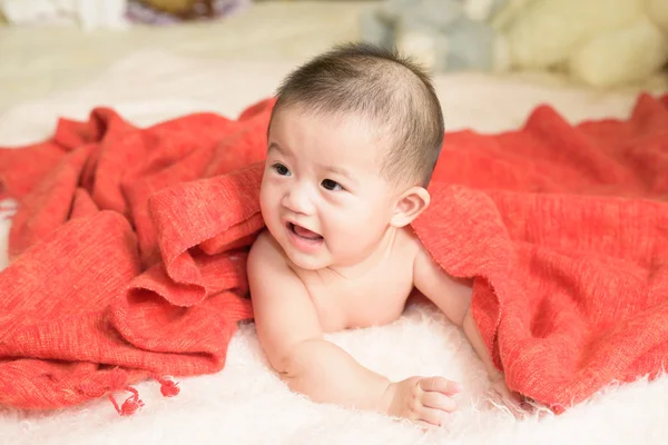 Asian baby girl is wrapped in orange blanket