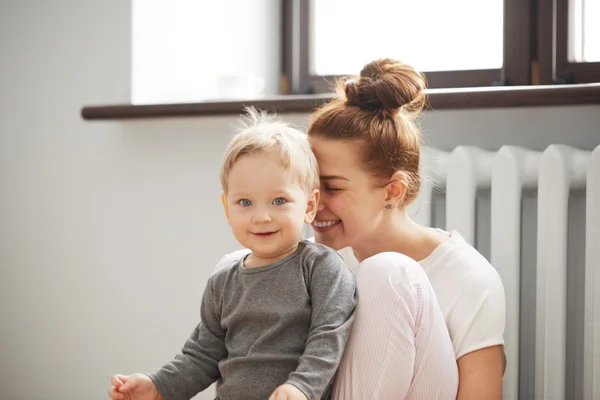 Happy young mother with little son on bedroom home background