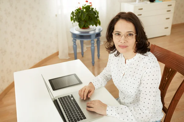 Portrait of a asian mature beautiful businesswomen thinking or brooding, work on portable laptop computer, charming adult female using net-book while sitting in office or home interior.