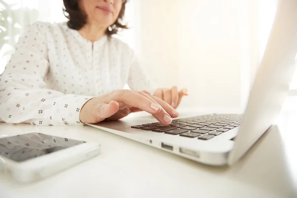 Closeup of businesswoman typing. Beautiful asian mature woman\'s hands busy working on laptop computer while work at the officework, woman sitting at the table with open net-book in office interior