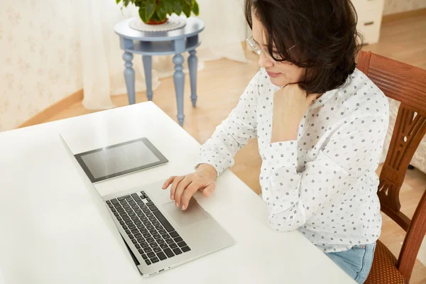 Portrait of a asian mature beautiful businesswomen thinking or brooding, work on portable laptop computer, charming adult female using net-book while sitting in office or home interior.