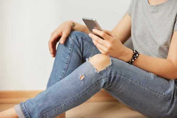 Closeup image of a teenager is searching information in network on mobile phone during free time. Young female student is revising photos on her cell telephone during break between lectures