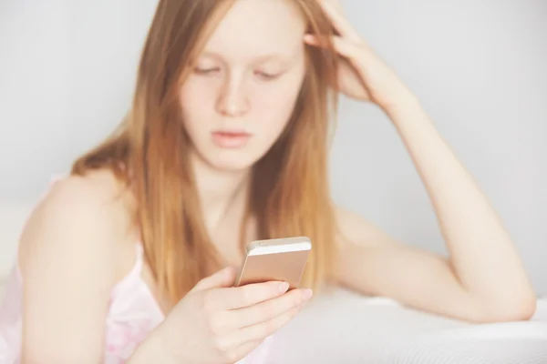 Closeup image of a teenager is searching information in network on mobile phone during free time. Young female student is revising photos on her cell telephon at home.