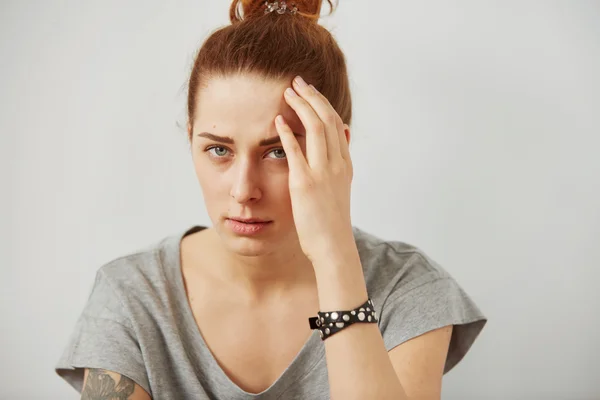 Closeup portrait young upset sad woman thinking deeply about something with headache holding her hands on head looking stressed isolated on gray wall background. Negative human facial expression