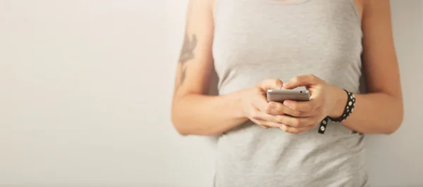 Cropped shot view of a woman's hands holding mobile phone, young female person chatting on cell telephone during work break.