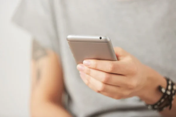 Cropped shot view of female hands holding cell phone, young woman texting on mobile telephone during work break on the gray background
