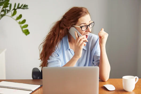 Headshot of a successful businesswoman looking excited talking on the cell phone. Portrait of a female freelancer shouting with excitement and joy. Attractive female manager winning business sitting i