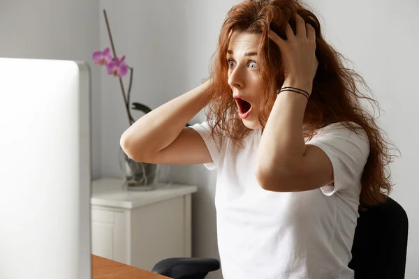 Pretty student girl having trouble with her laptop, looking in panic at the screen, holding her head. Frightened businesswoman with critical computer hanging problem. Negative human face expressions
