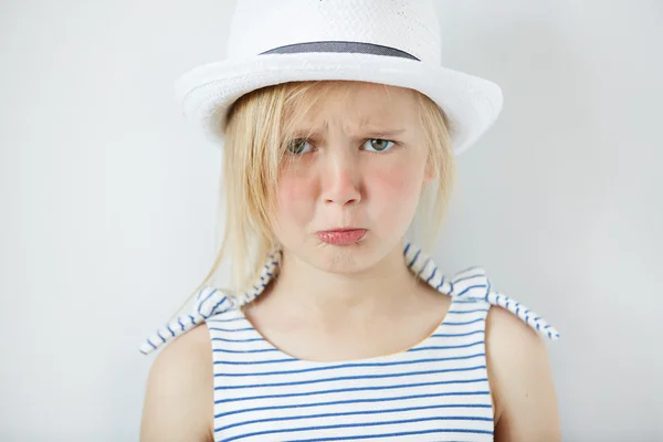 Studio portrait of sad little girl in stylish clothes crying and acting naughty, looking at the camera with angry expression, having trouble with going to bed. Human face expressions and emotions