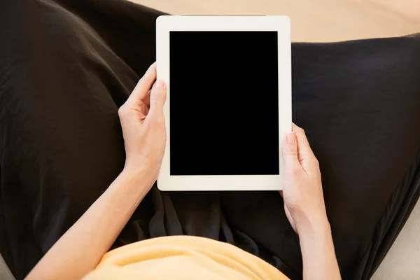 Cropped image of businesswoman browsing Internet while sitting on comfortable sofa at home. Female entrepreneur checking email and reading news on electronic device in the evening before going to bed