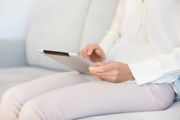 Cropped portrait of female freelancer working on digital tablet indoor. Young woman reading e-book or online magazine on electronic device while resting at home after hard working day in the office