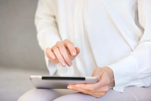 Cropped view of female using tablet computer with touch screen, messaging via social networks, reading news or watching pictures or videos. Close up shot of woman\'s hands holding electronic gadget