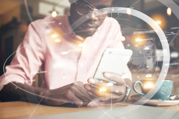 Double exposure. Visual effects. Futuristic technology and connection. Young African freelancer or office worker checking email or reading news on the Internet using smart phone. Selective focus