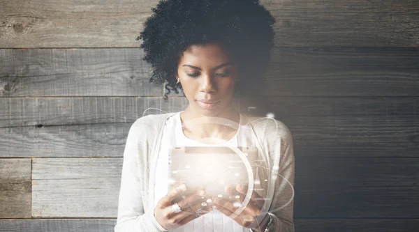 Futuristic technology and communication concept. Smiling pretty black girl with Afro hairstyle using digital tablet, checking email or typing a message. Visual effects. Worldwide connection interface