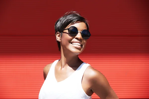 Cute female model with short hairstyle looking at the camera, showing her ultra-white smile, having fun while posing against red wall background with copy space for your text or advertising content