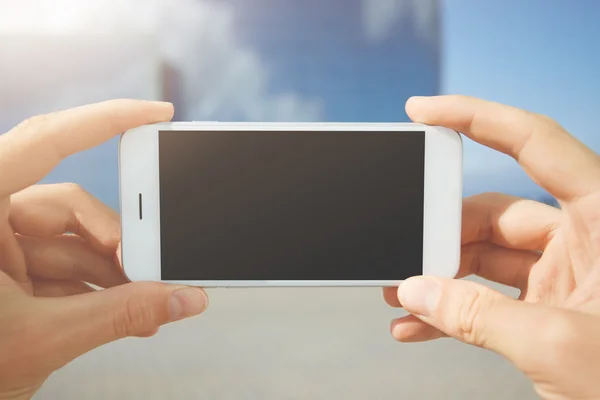 Close up shot of man\'s hands holding generic mobile phone with copy space touch screen for your advertisement against blue-sky background. Man watching pictures using wireless Internet connection