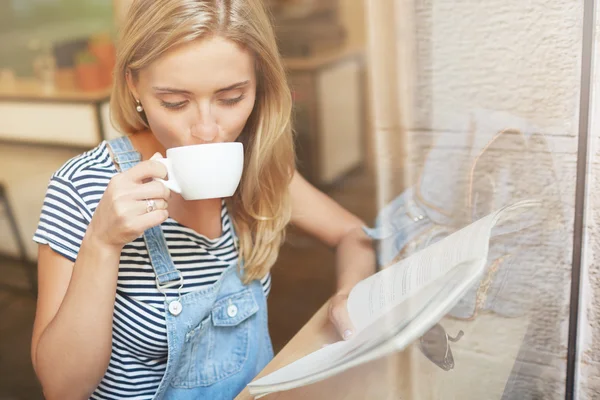 Woman sipping coffee and reading magazine