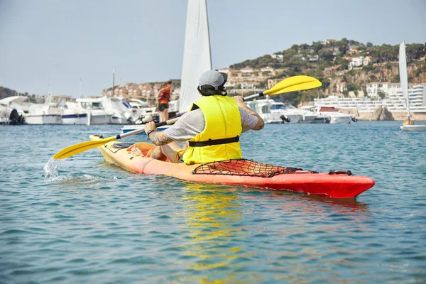 Man with tattoos paddling kayak