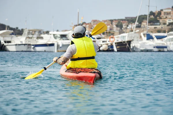 Hipster in surviving vest paddling kayak