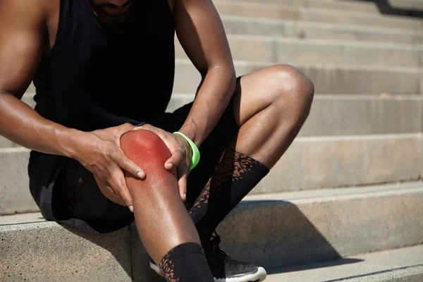 African athlete clutching his injured knee