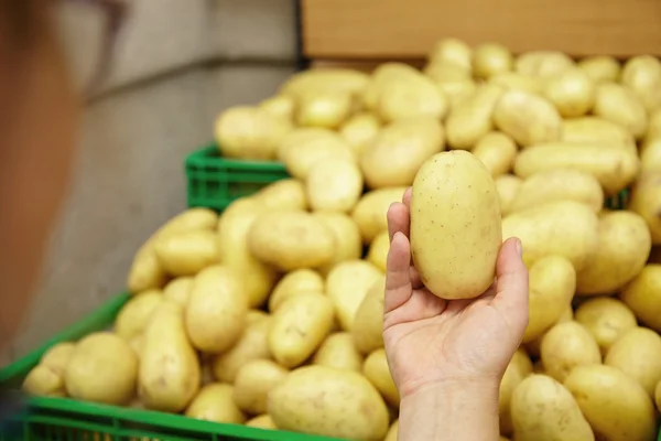 Housewife holding potato in city market