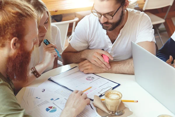 Young entrepreneurs working on common start-up project. Man in hipster glasses having brainstorm session with his colleagues, trying to find brand new innovative solutions for their business