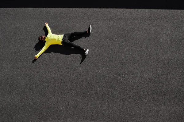 Top view runner in yellow sportswear resting lying on a black as