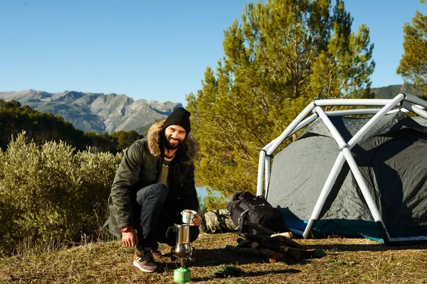 Adventure hiking man drinking coffee near tent. Smiling happy ma