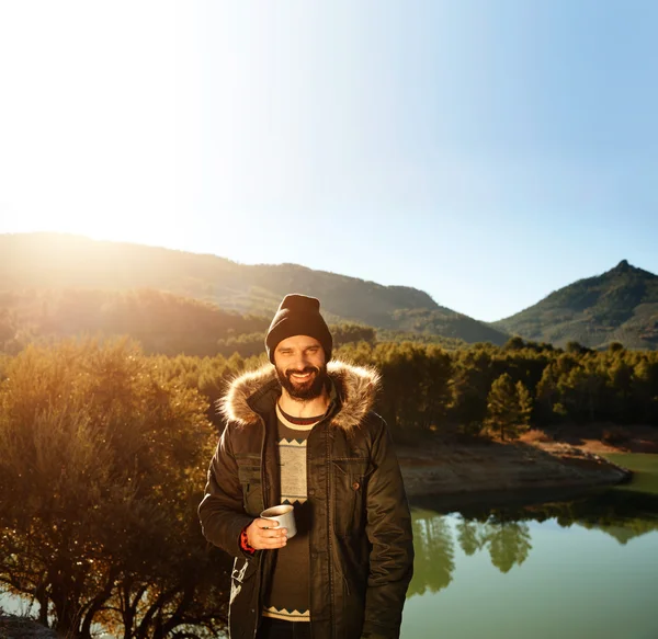 Strong hiker standing on the mountain near lake in background an