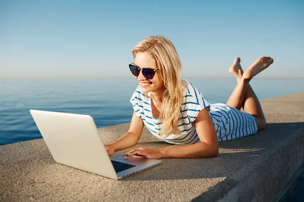 Cheerful girl lying at summer on the beach near sea and talks to