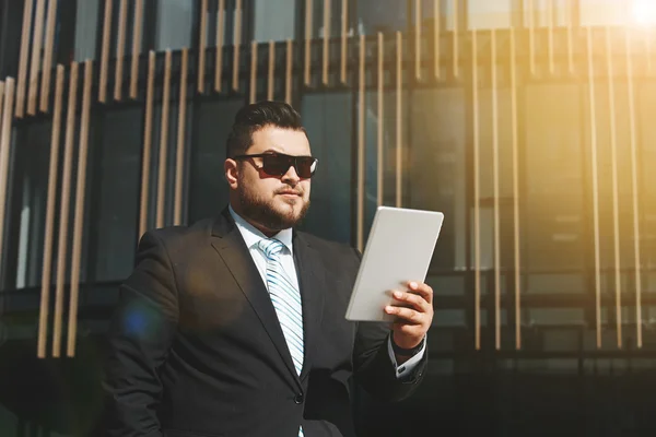 Portrait of business man reads news on tablet while standing in