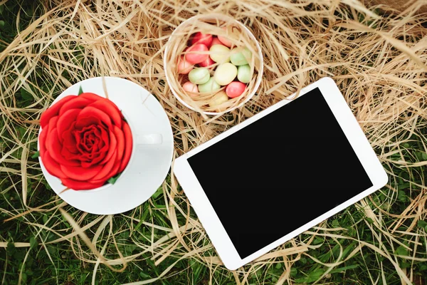 Top view digital tablet lying on wooden box with cookies, flower