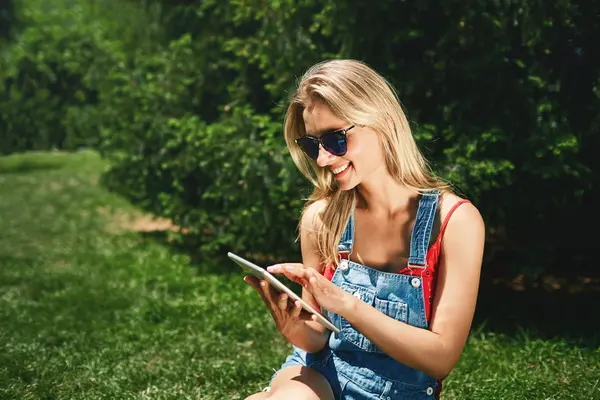 Portrait of happy young blonde woman college student use tablet