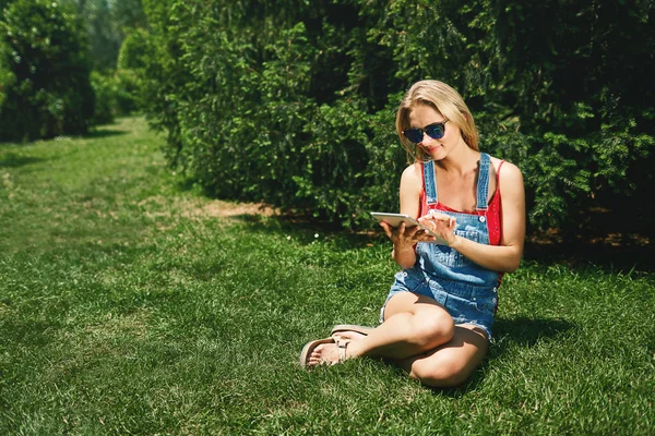 Happy young blonde woman college student use tablet pc sit on gr