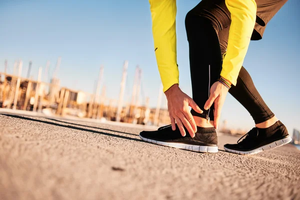 Broken twisted ankle - running sport injury. Athletic man runner touching foot in pain due to sprained ankle.