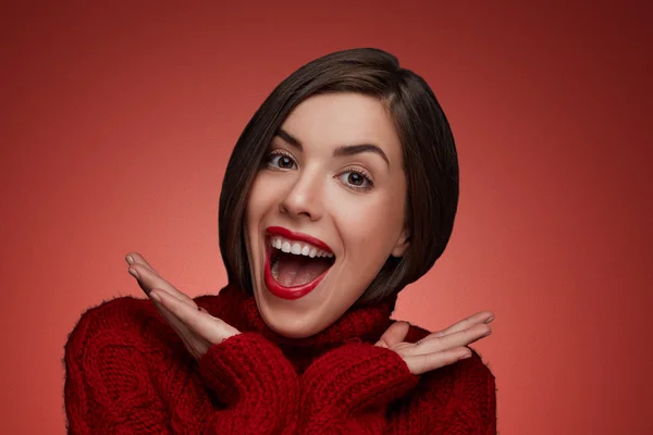 Winter beauty young woman portrait,model creative image with makeup. Funny laughing surprised woman portrait with open mouth standing around snow isolated. True Emotions. Red lips and red sweater.