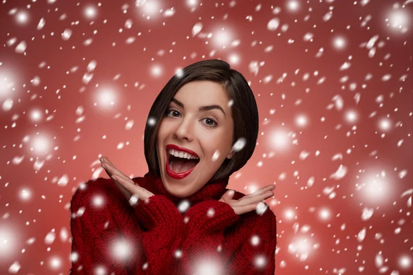 Winter beauty young woman portrait,model creative image with makeup. Funny laughing surprised woman portrait with open mouth standing around snow isolated. True Emotions. Red lips and red sweater.