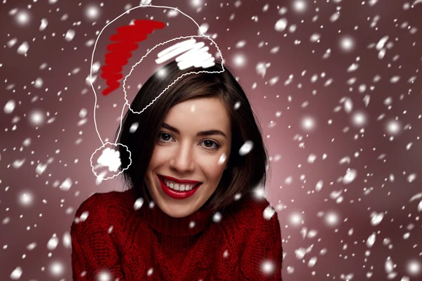 Christmas woman. Beauty model in santa hat and red sweater standing around snow isolated. Funny laughing surprised woman portrait with open mouth. True Emotions. Red lips. Beautiful holiday makeup.