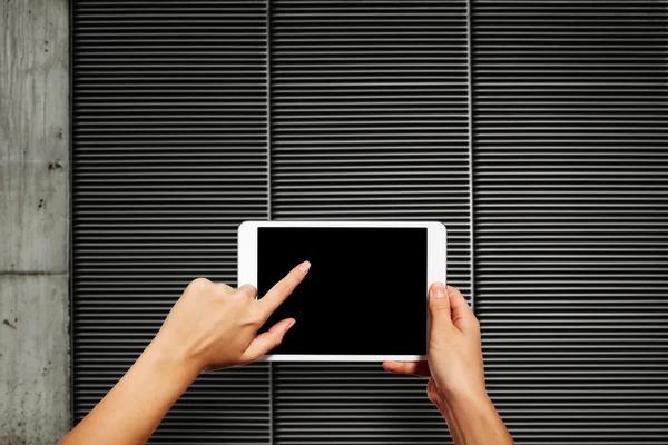Woman hands holding electronic tablet pc with blank screen. Isolated against texture wall background with copy space.