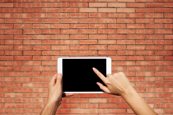 Woman hands holding electronic tablet pc with blank screen. Isolated against texture wall background with copy space.