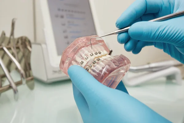 Prosthetics hands while working on the denture, false teeth, a study and a table with dental tools. Dental laboratory.