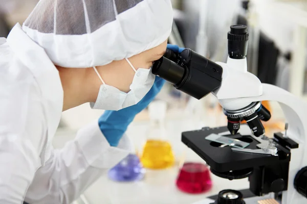 Young woman medical researcher looking through microscop slide in the life science (forensics, microbiology, biochemistry, genetics, oncology) laboratory. Medicine concept.